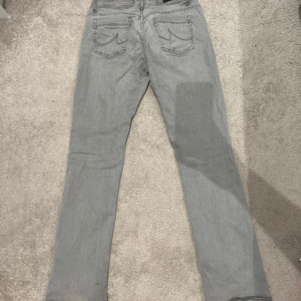 Snygga grå jeansbyxor med en klassisk design. De har en knapp och dragkedja framtill samt fem fickor. Perfekta för en avslappnad stil.. Farkut & Housut.