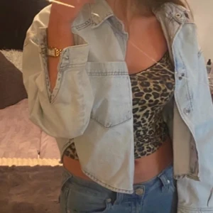 Ljusblå croppad jeansjacka - Ljusblå croppad jeansjacka med knappar framtill. Den har slit på båda sidorna som visas på bilden, knappen högst upp vid kragen går inte att knäppa men är osäker på om den ska göra det då det var så när jag köpte den, säljer då den inte kommer till användning😊