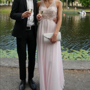 rosa balklänning  - Säljer min super fina balklänning med glittriga paljettdetaljer på överdelen och har en öppen rygg. Klänningen har en v-ringad design och korsade axelband bak. Storlek xs, den är uppsydd för mig som är 170cm + 5cm klackar, kemtvättad och ren! Köpt ny för ca 4200kr. kan fixa mer bilder & pris går såklart att diskutera :))