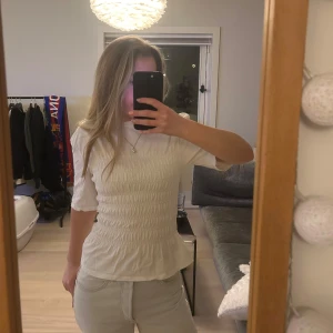 Vit topp från & Other Stories - Säljer en stilren vit topp från & Other Stories med trekvartsärm och smockdetaljer som ger en snygg passform. Perfekt för både vardag och speciella tillfällen. Toppen har en rund hals och är tillverkad i ett mjukt material. Endast använd en gång💕