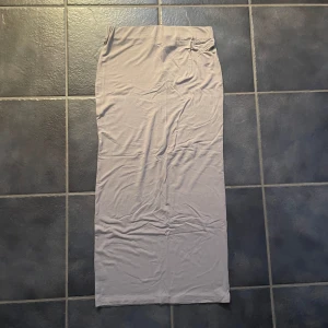 Beige långkjol från 5T - Snygg beige långkjol från 5T i en mjuk och bekväm polyesterblandning. Perfekt för en stilren och minimalistisk look. Kjolen har en enkel design utan mönster eller detaljer.