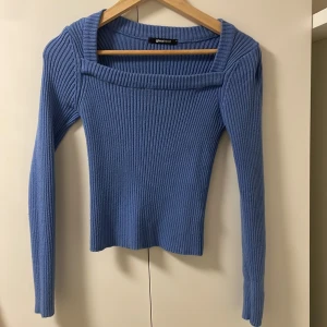 Blå ribbad tröja från Gina Tricot - Snygg blå ribbad tröja från Gina Tricot med fyrkantig halsringning. Tröjan har långa ärmar och en tight passform, perfekt för kyligare dagar. 