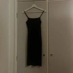 Svart klänning - Svart medellång klänning med axelband. Sitter kroppstajt. 