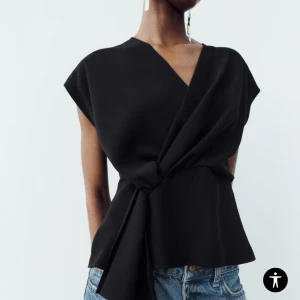 Svart omlottopp - Elegant svart omlottopp med v-ringning och knytning i midjan. Perfekt för en stilren look.  De ni är aldrig använd ny med pris lapp🥰 strl M