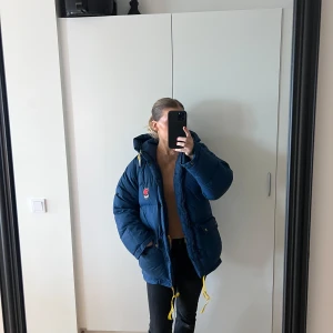 Fjällräven jacka  - En mörkblå fjällräven jacka. Finns inga tydliga defekter, endast att bandet man hänger upp jackan med har gått av (se bild 4) och att den saken på snöret har lossnat (se bild 5). Det finns fler sånna på jackan som man hade kunnat byta plats på o sätta dit på det snöret där de saknas. Annars är jackan i mycket fint skick! Jackan är i storlek 36/38 men passar mig som normalt har xs/s. Jag är 163. 