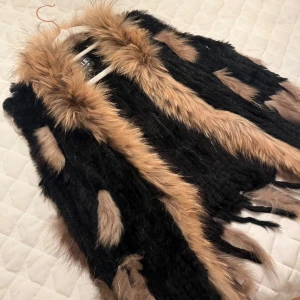 Svart och brun pälsväst från Hollies - Säljer en snygg svart och brun pälsväst från Hollies i storlek M. Västen har ett iögonfallande mönster med fluffiga detaljer och är perfekt för att hålla sig varm och stilren.