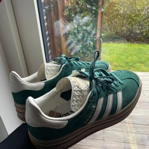 Adidas Gazelle i grön mocka - Snygga Adidas Gazelle sneakers i grön mocka med vita detaljer. Använda endast 2 gånger! Nypris 2200kr