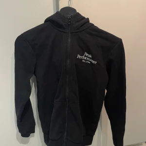 Svart fleecejacka från Peak Performance - Säljer en svart fleecejacka från Peak Performance med dragkedja och broderad logga på bröstet. Jackan har långa ärmar och en hög krage för extra värme. Perfekt för kyliga dagar.