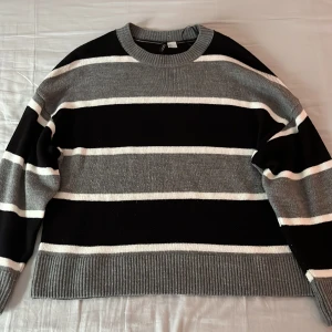 Randig tröja från H&M Divided - Säljer en randig tröja från H&M Divided i svart, grått och vitt. Tröjan har en avslappnad passform med ribbade muddar vid ärmslut och nederkant. Tröjan är i väldigt bra skick. Säljer den eftersom jag inte använder den längre. Perfekt för en höstlig look! (Nypris: 200 kr)