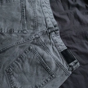 Grå jeansbyxor - Snygga grå jeansbyxor med klassisk femficksdesign. De har en rak passform och är perfekta för en avslappnad stil. Byxorna har en dragkedja och knapp framtill.