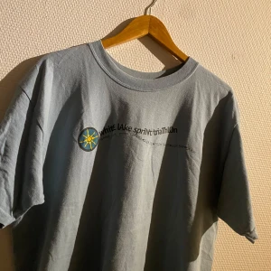 Turkos/ljusblå T-shirt  - Säljer en t-shirt från Gildan med tryck för White Lake Sprint Triathlon. T-shirten har korta ärmar och är tillverkad i bomull. Perfekt för sportiga tillfällen eller som en casual vardagströja.