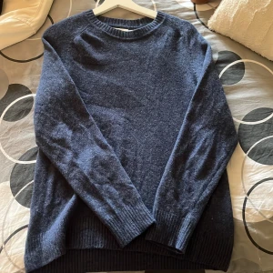 Mörkblå stickad tröja - Säljer en mysig mörkblå stickad tröja från märket Grandpa som är perfekt för kyliga dagar. Tröjan har långa ärmar och ribbstickade muddar vid ärmslut och nederkant. Den är i bra skick, nypris går för 1200kr