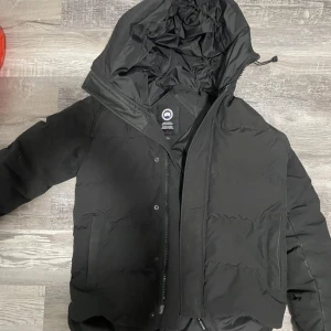 Canada Goose Macmillan Parka Black Jacka - Jackan är i utmärkt skick, använd under vintern 2023/2024. Eftersom den inte passar för den kommande vintern, vill jag sälja den snabbt för att kunna köpa en ny innan kylan kommer. Priset är sänkt på grund av att knappen längst nere lossnat men annars är den top skick.