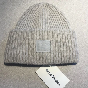 Grå ribbad mössa från Acne Studios - Snygg grå ribbad mössa från Acne Studios med märke framtill. Ny med lappen kvar. Ursprungligen 1600