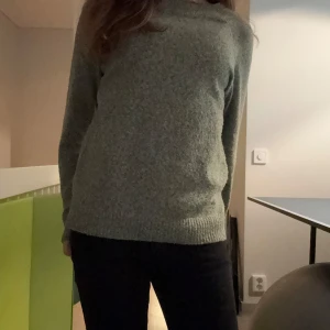 Grön stickad tröja - Mysig grön stickad tröja med långärmad design. Perfekt för kyligare dagar med sin bekväma passform och klassiska stil.