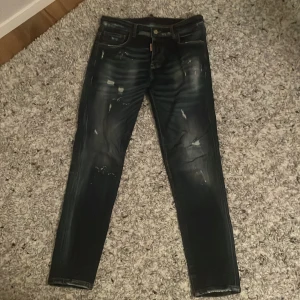 Svarta jeans från Dsquared2 - Snygga svarta jeans från Dsquared2 med slitna detaljer och en cool tvätt. De har en knappgylf och klassisk femficksdesign. Perfekta för en trendig look.