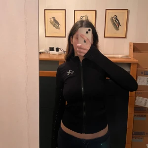 Svart träningsjacka med dragkedja - Snygg svart träningsjacka. Jackan har en tight passform och stretchigt material. Använt den några gånger och är i ett jätte bra skick, den sitter jätte bra och formar kroppen. 