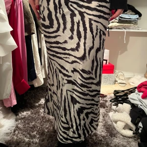 Zebramönstrad långkjol - Snygg zebramönstrad långkjol i svart och vit. Perfekt för att sticka ut med ett djärvt mönster. Kjolen har en elegant passform och är ett måste för garderoben.