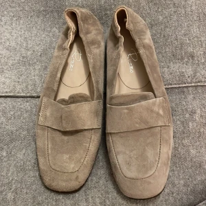 Beige mockaloafers från Rizzo - Snygga beige loafers i mjuk mocka från Rizzo. Perfekta för en stilren look med en bekväm passform. Skorna har en klassisk design med en bred rem över foten.