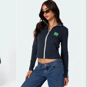 Mörkblå tröja med Brasilien-tryck - Snygg mörkblå jacka från Edikted med Brasilien-tryck på bröstet. Orginalpris: 335 kr. Perfekt för en sportig look!