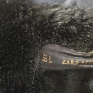 Blå parkajacka med fuskpäls från Zara - Snygg blå parkajacka från Zara med fuskpäls på huvan. Jackan har dragkedja och knäppning framtill samt praktiska fickor. Perfekt för kyliga dagar.