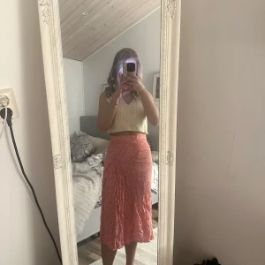 Röd kjol - Snygg röd kjol i ett lätt och luftigt material. Kjolen har en omlott-design och når till mitten av vaden och med en liten slits på sidan , vilket ger en elegant look. Perfekt för varma dagar.