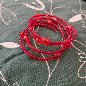 Rött pärlarmband - Snyggt rött armband med små och stora pärlor. Armbandet är av metall och kan enkelt anpassas till handleden. Perfekt för att ge en färgklick till din outfit.