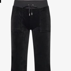 Svarta byxor med snörning - Snygga svarta byxor med hög midja och snörning i midjan. Byxorna har praktiska fickor med knappar baktill och är tillverkade i ett mjukt material som liknar mocka. Perfekta för en stilren look.