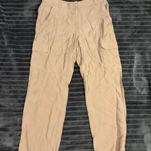 Beige cargobyxor - Säljer ett par beige cargobyxor med flera praktiska fickor. Byxorna har en loose passform och är perfekta för en avslappnad stil. De är tillverkade i ett slitstarkt material och har en midwaist design.