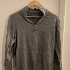 Grå halvzip från Gant - Säljer en stilren grå tröja från Gant med halv dragkedja och broderad logga på bröstet. Tröjan har långa ärmar och en hög krage som ger en skön look. Perfekt nu under vintern och även i vår. Kontakta mig gärna vid några frågor!