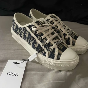 Dior sneakers - Snygga sneakers från Dior med ett ikoniskt mönster i blått och vitt. Skorna är i bra skick och med skorna kommer det box, påse, dustbag, äktighetsbevis och andra skosnören. Skriv ifall ni har fler frågor 💕