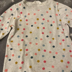 Barn Prickig tröja från H&M  - Säljer en söt tröja från H&M med färgglada prickar i rosa, blått och gult på en ljusgrå bas. Helt nya barnen har aldrig använt
