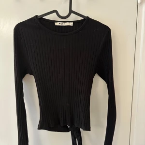Svart ribbad tröja från NA-KD - Snygg svart ribbad tröja från NA-KD med långa ärmar och öppen rygg med knytning!🫶🏻