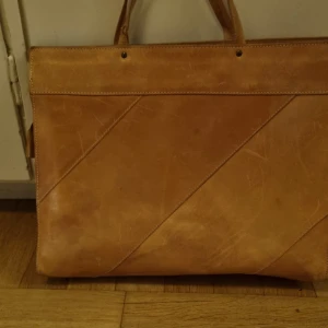Brun skinnväska med dragkedja - Snygg brun skinnväska med praktisk dragkedja och stilren design. Perfekt för att bära med sig det nödvändigaste. Väskan har ett rymligt fack och en mindre ficka med dragkedja inuti.