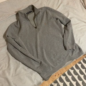 Ralph lauren quarter zip  - Grå Ralph lauren quarter zip i princip i nyskick. Endast använd ett fåtal gånger och har inga skador eller fläckar. Small i storlek. Säljes pga att storleken inte var den jag letade efter.