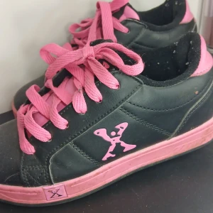 Svarta och rosa rullskor från Sidewalk Sports - Coola svarta rullskor med rosa detaljer och snörning från Sidewalk Sports. Skorna har inbyggda hjul i sulan för att enkelt kunna rulla fram. Perfekta för den som vill kombinera sneakers med rullskor.