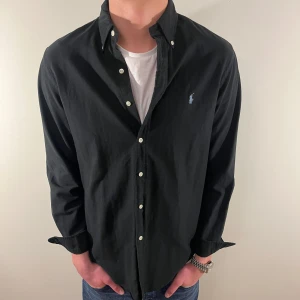 Svart skjorta Ralph Lauren skjorta (blått märke) - Nu säljer vi ännu en fet polo skjorta som passar till alla tillställningar och skjortan är i mycket bra skick! Du ska kunna uttrycka stil utan att det kostar för mycket!🕺🍾💼🤩  Storlek👔: M Nypris💰:  ca 1499kr