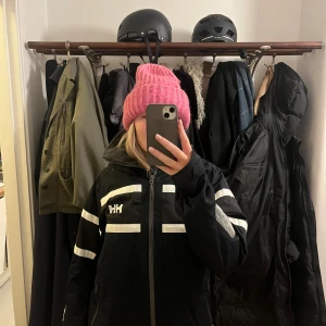 Navy blue skidjacka från Helly Hansen - Säljer en svart vindjacka från Helly Hansen med vita detaljer och dragkedja. Jackan har långa ärmar. Används som skidjacka. Sparsamt använd. Navy blue/svart  