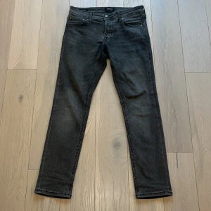 Svarta jeans från Jack & Jones - Snygga mörk gråa jeans från Jack & Jones i en klassisk slim fit. De har fem fickor och en knappgylf. Perfekta för en stilren look. byxorna är använda några få gånger och har inga tecken på skador eller slitage hör av dig om du har några funderingar👍