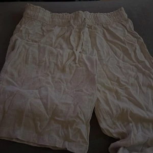 Vita linne byxor med snörning - Säljer ett par vita linnebyxor  med elastisk midja och snörning. Perfekta för en avslappnad stil under varma dagar.