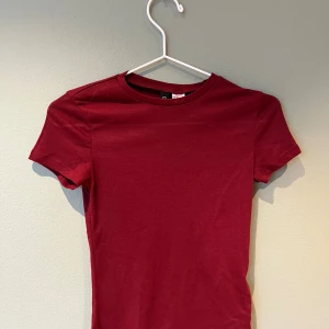 Vinröd t-shirt från H&M Divided - Säljer en stilren vinröd t-shirt från H&M Divided. Den har en klassisk rund hals och korta ärmar, perfekt för en enkel och snygg look. Lite genomskinlig men as snygg!💕💕