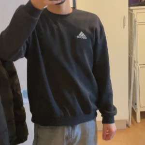 Svart Adidas sweatshirt - Säljer en stilren svart sweatshirt från Adidas på storlek M. Tröjan har långa ärmar och en rund halsringning. Perfekt för en avslappnad look eller träning. Skicket på den är 8/10! Pris går att diskuteras!
