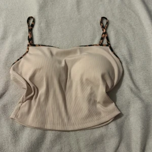 Beige ribbad linnetopp från Shein - Säljer en beige ribbad linnetopp från Shein med leopardmönstrade axelband. Perfekt för en stilren och trendig look. Tillverkad i mjukt och stretchigt material för extra komfort. Även inbyggdbh