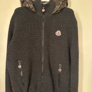 Moncler cardigan  - Moncler hooded cardigan. Slutsåld modell och rare färg (grå/olivgrön) super fint skick som ny. Storlek M. Pris 4890kr.