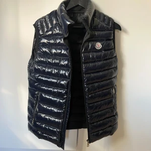 Moncler väst  - Säljer denna super fina västen, den är i bra skick förutom att dragkedjan inte går att stänga så den måste fixas om man inte vill ha västen öppen bara/ inget som syns dock , storlek M