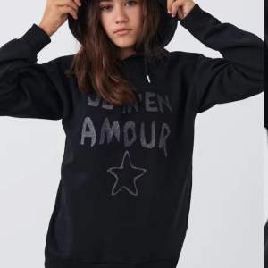 Säljer en snygg svart hoodie från Gina Tricot med texten 'Je m'en amour' och en stjärna på framsidan. Den är perfekt för vintern och har långa ärmar och en mysig huva. Passar perfekt för höst och vinter! Skicket är som nytt har andvänt 2-3 gånger 