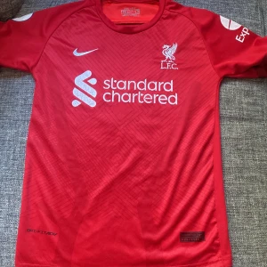 Fotbolls tröja  - Storlek 176, Mohammed Salah nr 11, Liverpool tröja. Säljer för den har blivit förliten för mig. Bokstäverna är ganska slitna men annars så är tröjan i fint skick.