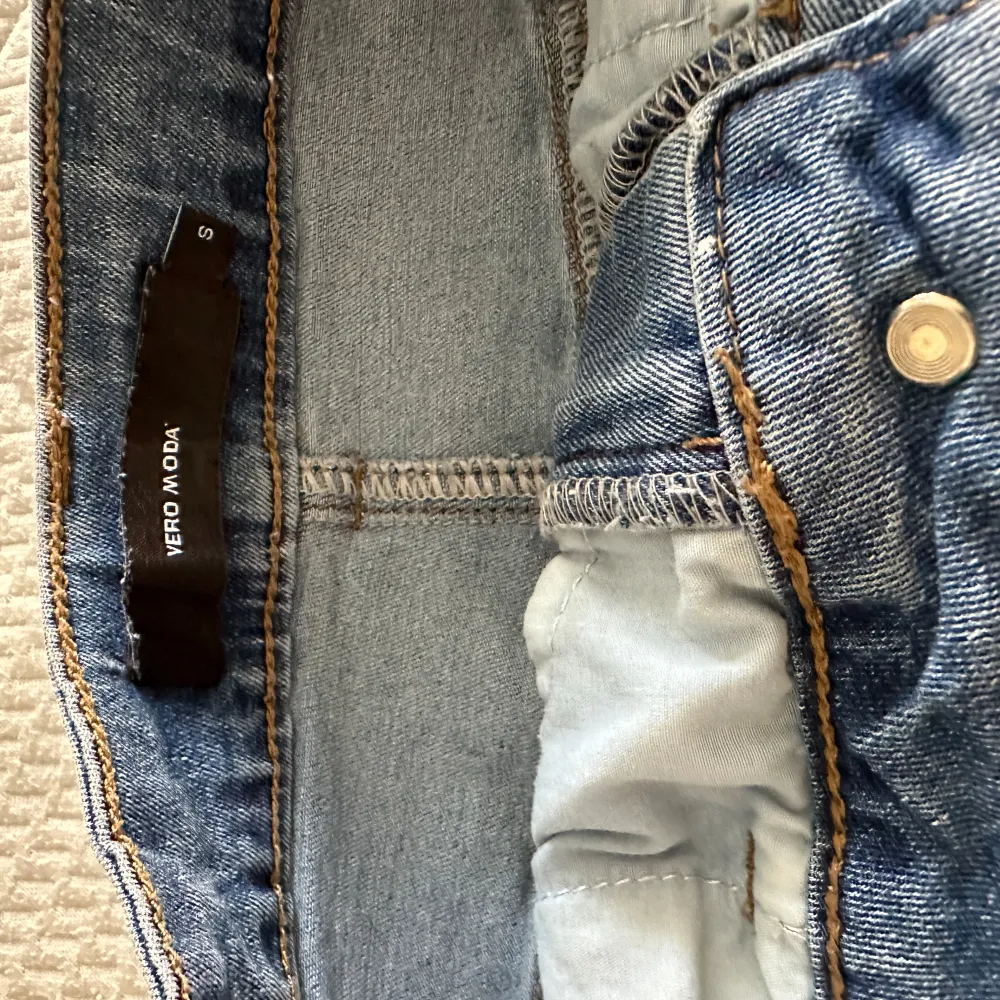 Säljer en snygg jeanskjol från Vero Moda i storlek S. Kjolen har en klassisk blå denimfärg och är i en normal passform. Den har både fram- och bakfickor samt en slits baktill för extra rörelsefrihet. Perfekt för en avslappnad vardagslook!. Kjolar.