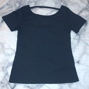 Svart t-shirt med öppen rygg - Lappen inuti tröjan är sliten men själva tröjan är i bra skick och har inga fläckar!
