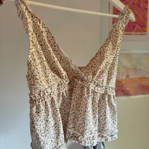 Blommig topp från Shein - Säljer en söt blommig topp från Shein i storlek L. Toppen är ärmlös och har ett elastiskt band under bysten för en bekväm passform. Perfekt för sommardagar eller en avslappnad fest. Materialet känns lätt och luftigt, vilket gör den idealisk för varma dagar. 🌸 Bra skick. 